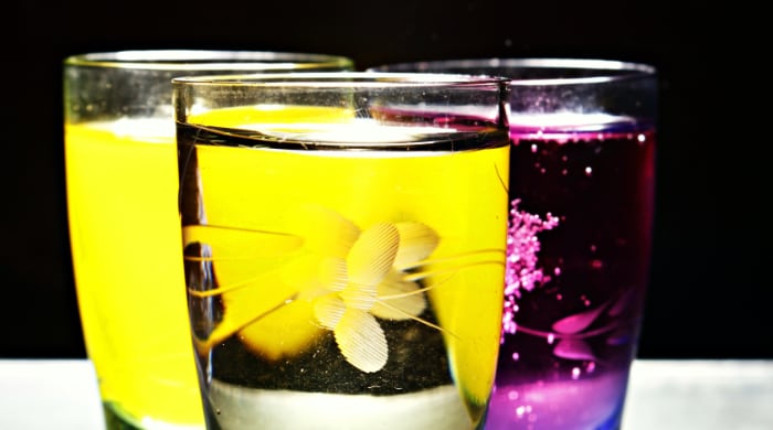 Three glasses in triangle with water in front and orange and blackberry juice showing through
