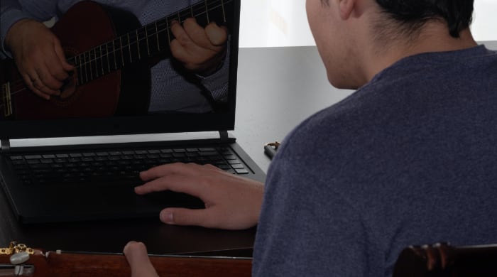 Young man learning guitar online